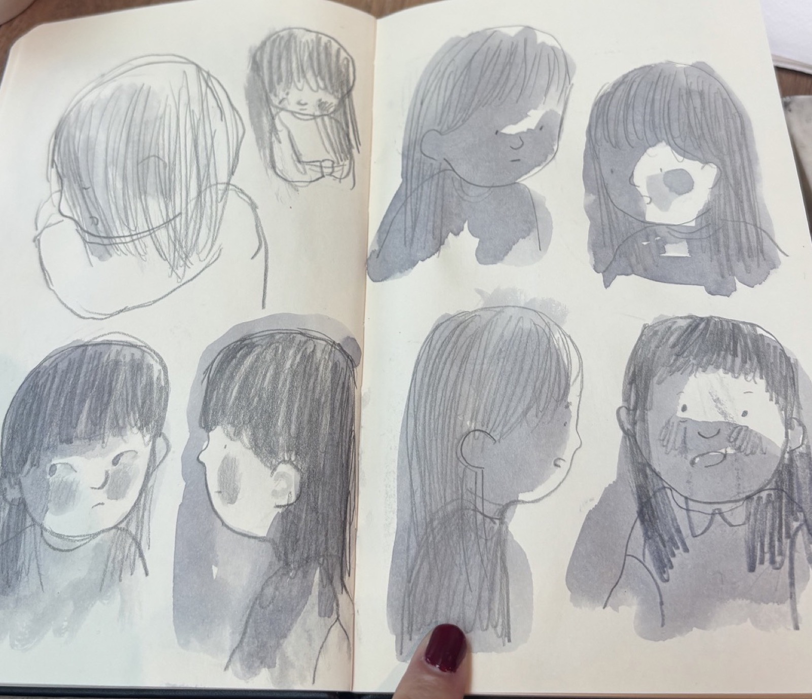 Eight small heads — pencil and ink wash, a sketchbook spread